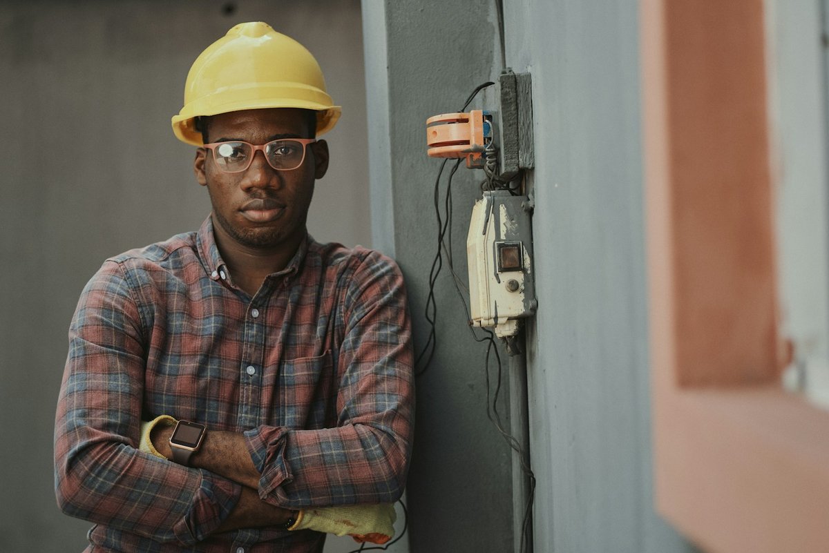 Electrician in a hard hat beside an outdoor electrical panel